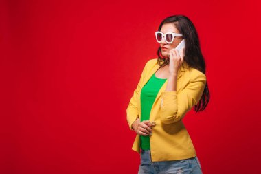 Telefonda konuşurken sarı ceketli kırmızı arka planlı kız