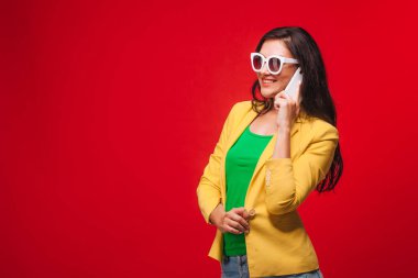 Telefonda konuşurken sarı ceketli kırmızı arka planlı kız