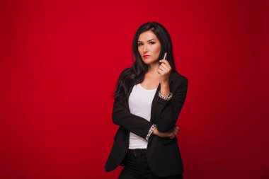 Kız kırmızı bir arka plan üzerinde dudaklarını boyar