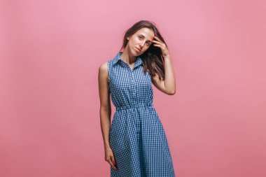 Kız düşünüyor ve pembe bir arka plan üzerinde başını tutarak