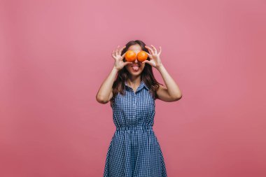 Kız portakal ile gözlerini kapattı ve pembe backg üzerinde dil gösterir