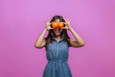 Kız portakal ile gözlerini kapattı ve pembe backg üzerinde dil gösterir