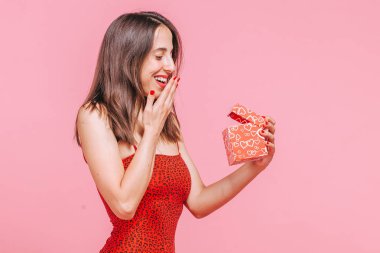 Kız bir hediye ile bir kutu aldı ve pembe bir backg üzerinde sevinir