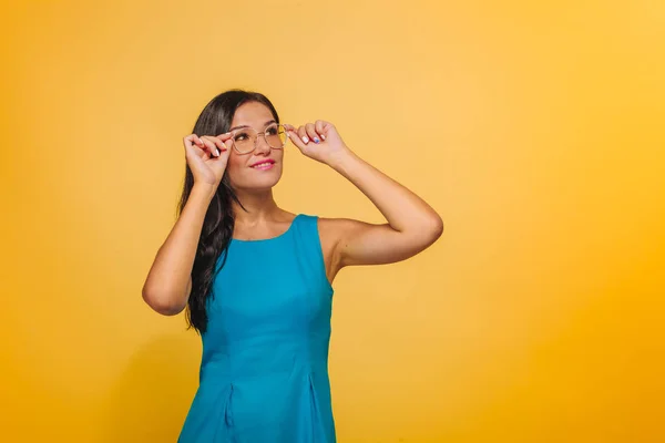 Menina em um fundo amarelo tocando óculos — Fotografia de Stock