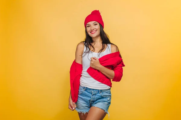 Menina no fundo amarelo em casaco vermelho e chapéu — Fotografia de Stock