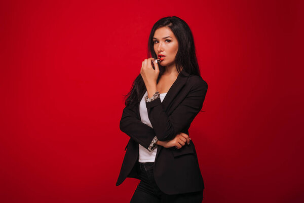 Girl paints her lips on a red background