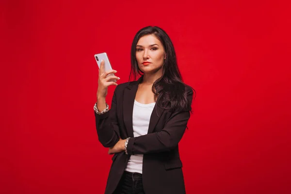girl in a business suit looking at the phone. On red background