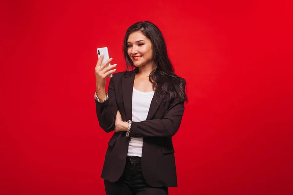 girl in a business suit looking at the phone. On red background