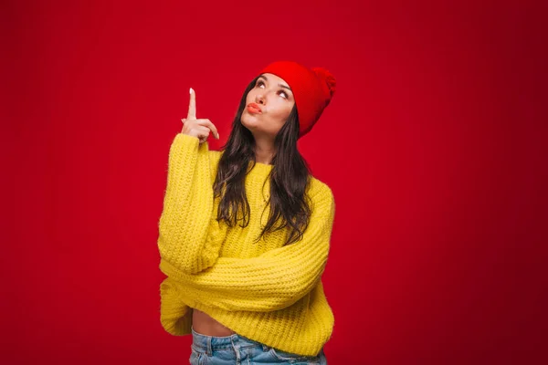 Menina em suéter amarelo e chapéu no fundo vermelho Mostra dedos u — Fotografia de Stock