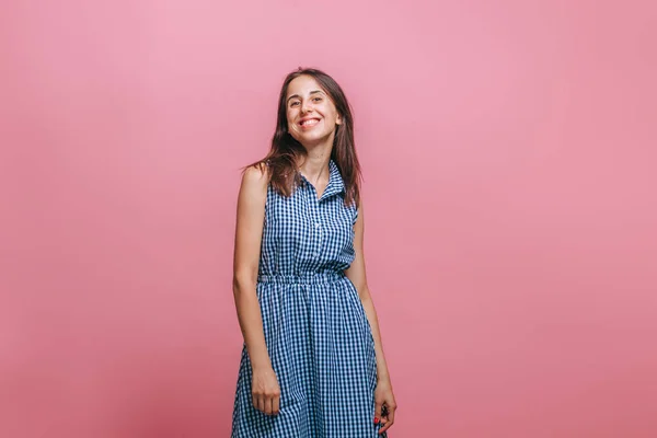 Una chica con un vestido azul está de pie sobre un fondo rosa y sonríe —  Fotos de Stock