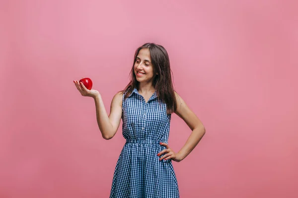 Menina segurando maçã vermelha no fundo rosa — Fotografia de Stock