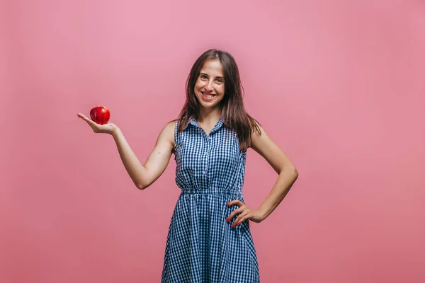 Menina segurando maçã vermelha no fundo rosa — Fotografia de Stock