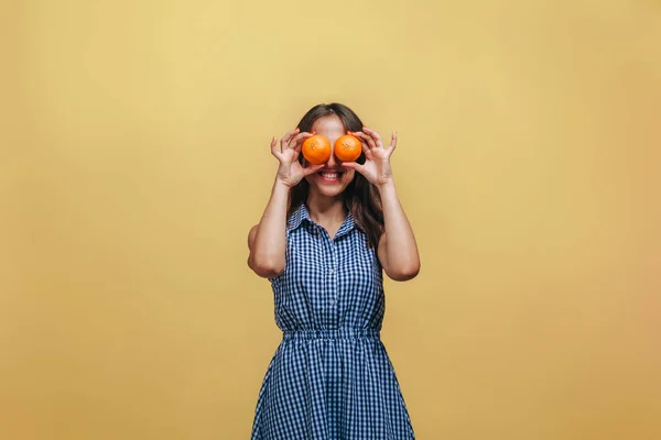 A menina fechou os olhos com laranjas em um fundo amarelo — Fotografia de Stock