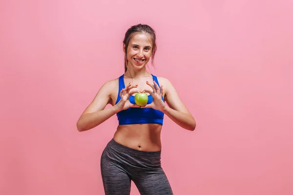 Menina magro segurando maçã verde no fundo rosa — Fotografia de Stock