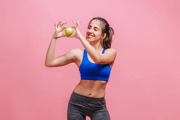 Menina magro segurando maçã verde no fundo rosa — Fotografia de Stock