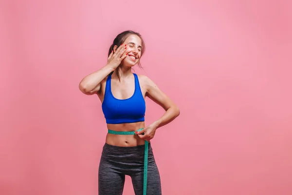 Menina mede a cintura e gosta de fundo rosa — Fotografia de Stock