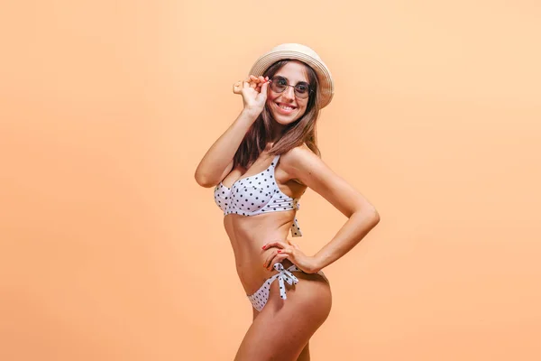 Chica en traje de baño con gafas de sol y sombrero sobre un fondo amarillo . — Foto de Stock