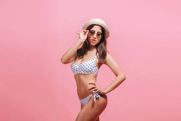 Chica en traje de baño gafas de sol y sombrero sobre fondo rosa . — Foto de Stock