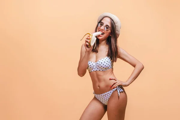 Chica comiendo un plátano sobre un fondo amarillo . — Foto de Stock