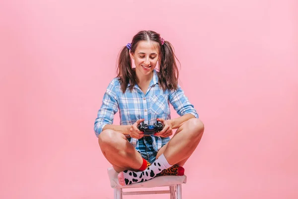 Девушка с игровым джойстиком, играющая в игры на розовом фоне — стоковое фото