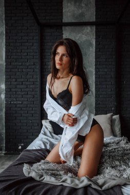 Siyah iç çamaşırı seksi esmer kız yatakta diz çöker