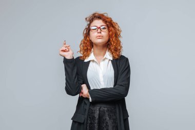 İş elbisesi ve gözlüklü kızıl saçlı bir kadın. 