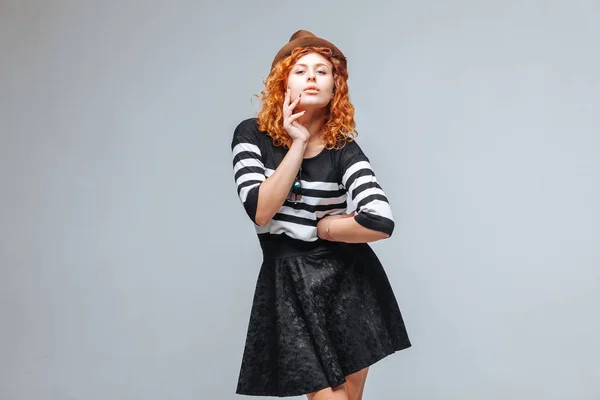 Red-haired girl posing in a hat on a gray background — Stock Photo, Image