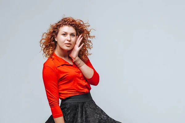 Red-haired girl in the wind in a skirt develops