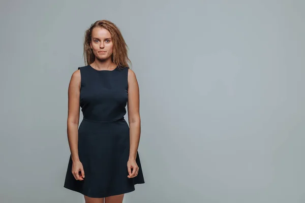 Hermosa chica con un vestido azul y posando en un backgro gris —  Fotos de Stock