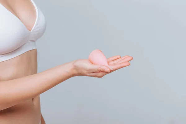 Chica sosteniendo copa menstrual sobre fondo gris claro — Foto de Stock