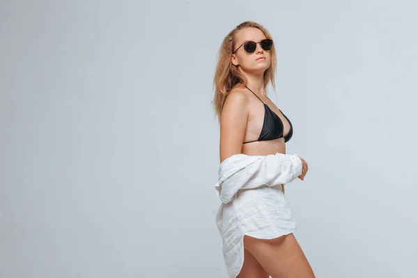 Girl in a black swimsuit and sunglasses and a white shirt on a l — Stock Photo, Image