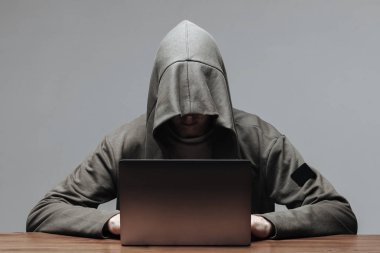 Bir dizüstü bilgisayarda oturan bir yüz olmadan bir başlık içinde Hacker
