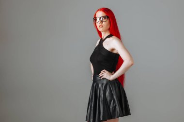 Gözlük ve deri etek posi giyen kırmızı uzun saçlı kız