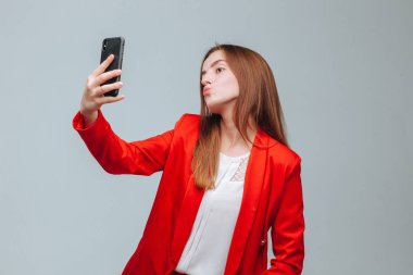 kırmızı ceketli kız gri bir backg telefonda bir selfie alır