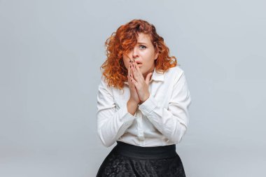 Kızıl saçlı kız gri bir arka plan üzerinde memnun