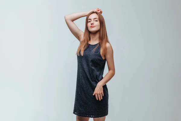 Chica en un vestido oscuro posando sobre un fondo gris —  Fotos de Stock