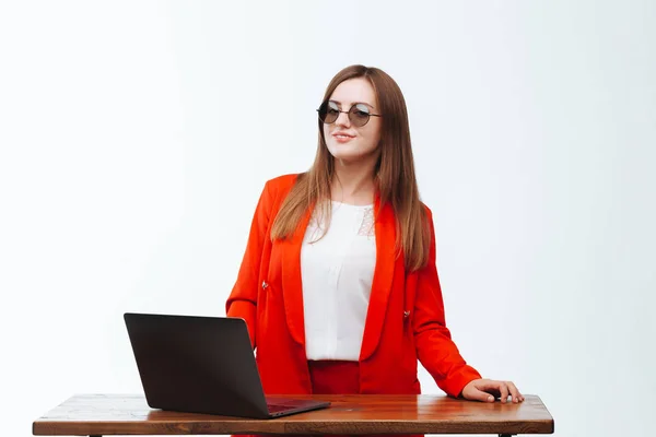 Sexy Mädchen in roter Jacke arbeitet am Computer an einem weißen Bac — Stockfoto