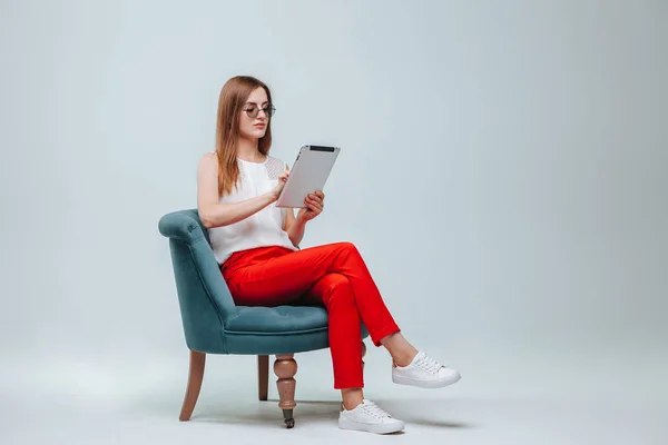 Mädchen arbeitet am Tablet sie ist in roter Hose, Brille und Sittin — Stockfoto