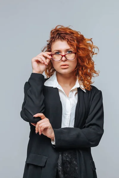 Rudowłosy Kobieta w garniturze i dotyka okulary — Zdjęcie stockowe