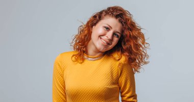 Açık gri arka plan smil üzerinde sarı bir elbise kırmızı kıvırcık kız