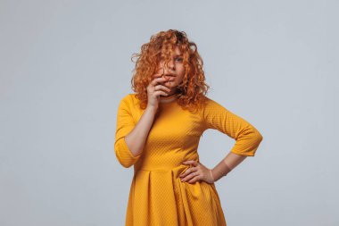 Redhaired kıvırcık kız açık gri bir arka plan üzerinde düşünüyor