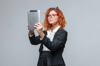 Açık gri arka plan üzerinde bir tablet ile kızıl saçlı kız