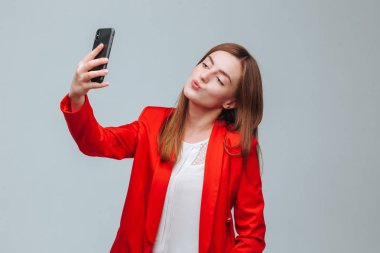 kırmızı ceketli kız gri bir backg telefonda bir selfie alır