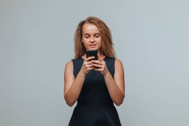 Mavi elbiseli bir kız telefonda bir gra üzerinde bir mesaj yazıyor