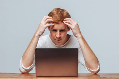 Bir adam hafif bir arka plan üzerinde bir dizüstü bilgisayar için düşünüyor