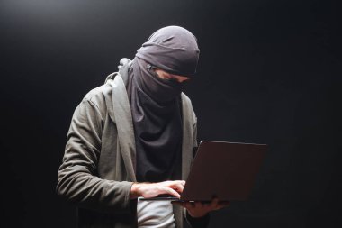 Siyah arka planda dizüstü bilgisayar ile Terörist