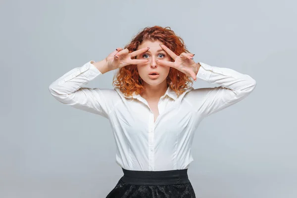 Una chica pelirroja con una camisa blanca muestra dos dedos —  Fotos de Stock