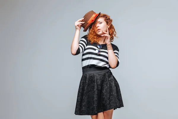 Chica pelirroja posando en un sombrero sobre un fondo gris —  Fotos de Stock