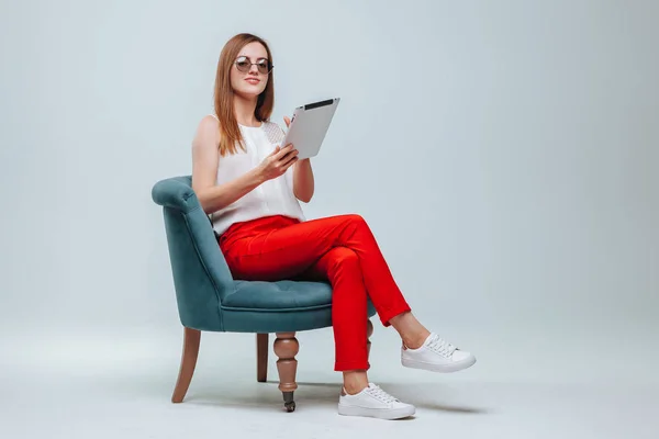Mädchen arbeitet am Tablet sie ist in roter Hose, Brille und Sittin — Stockfoto