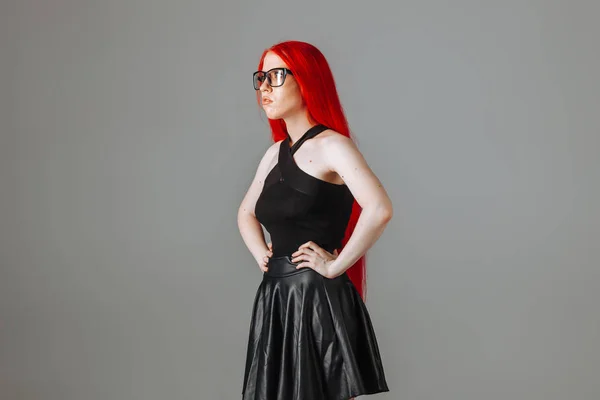 빨간 긴 머리를 가진 소녀 착용 안경 과 a 가죽 스커트 posi — 스톡 사진